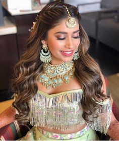 a beautiful woman in a green outfit with gold jewelry and earrings on her head is smiling at the camera