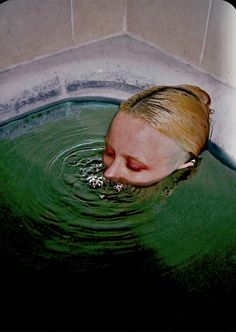 a woman in a bathtub with her eyes closed and head above the water's surface