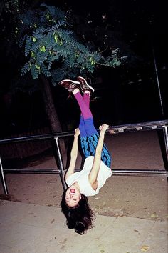 a woman is upside down on the ground with her feet up in the air while holding onto a railing