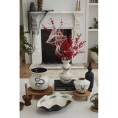 vases with red flowers in them sit on small trays next to a fireplace