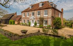 a large brick house sitting on top of a lush green field