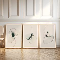 three framed art prints on the wall next to a chair in a room with white walls and parquet flooring