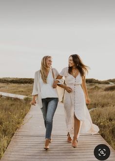 two women walking down a wooden walkway holding hands