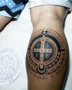 a tattoo on the leg of a person with a cross and compass in black ink