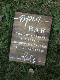 an open bar sign sitting in the grass