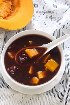 a white bowl filled with soup next to a cut up pumpkin on a table cloth