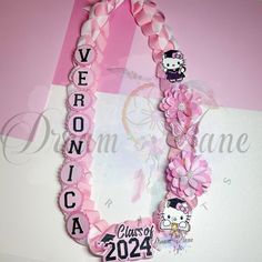 a pink ribbon necklace with hello kitty on it and the name class of 2024