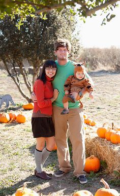 a man and woman standing next to each other in front of pumpkins on the ground