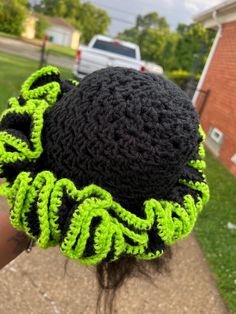 a close up of a person wearing a black and green crocheted hat on their head