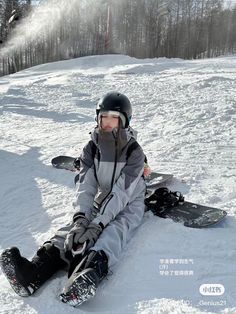 a young boy sitting in the snow with his snowboard attached to his feet, wearing a helmet and goggles