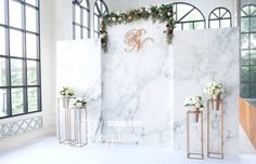 a white marble wall decorated with flowers and greenery