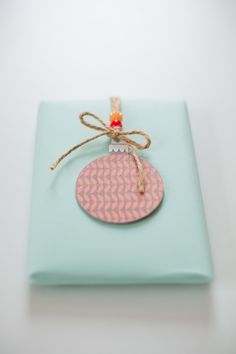 an ornament hanging from a string on top of a blue gift wrapper