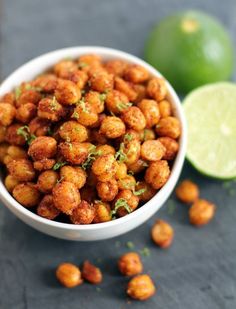 a white bowl filled with fried food next to lime