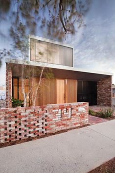 a brick wall with a wooden door on top of it next to a sidewalk in front of a house