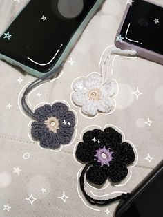 two cell phones are sitting next to each other with crocheted flowers on them