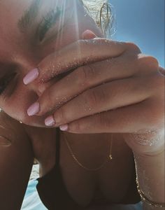 a close up of a person with her hands on their face and the sun shining behind her