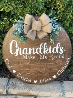 a wooden sign that says grandkids make life grand with a bow on it