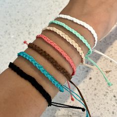 a woman's arm with four different colored bracelets on top of each other