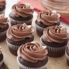 cupcakes with chocolate frosting sitting on a cutting board