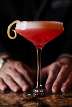 a close up of a person holding a glass with a drink in it on a table