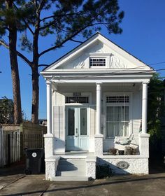 a small white house sitting next to a tree