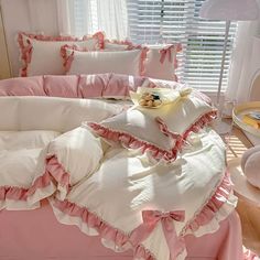 a bed with pink ruffled sheets and pillows