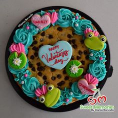 there is a cookie decorated with blue icing and pink flowers in the shape of a heart that says happy valentine's day