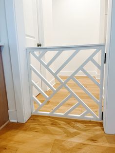 an open white gate in the corner of a room with wooden floors and hard wood flooring