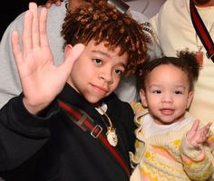 two children are posing for the camera with their hands in the air and one child is waving