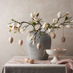 a vase filled with flowers and eggs on top of a table next to a bowl