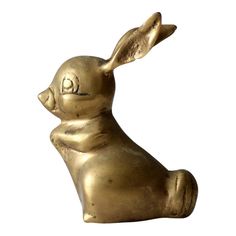 a gold colored rabbit statue sitting up against a white background