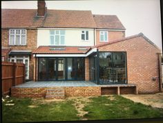 a large brick house with an extension to the back patio and covered in glass doors