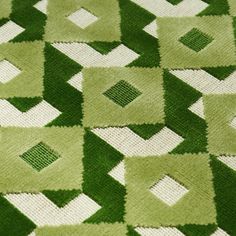 a green and white rug with squares on it's sides, in the shape of diamonds