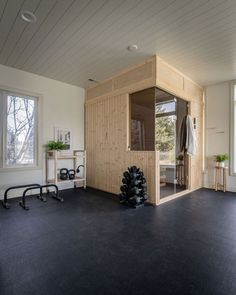 a room with black floors and white walls has a wooden structure on the wall, as well as two windows