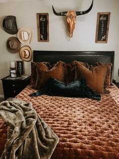 a bed with brown sheets and pillows in a bedroom next to pictures on the wall