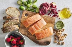 salmon, bread and berries on a cutting board next to other ingredients for a healthy meal