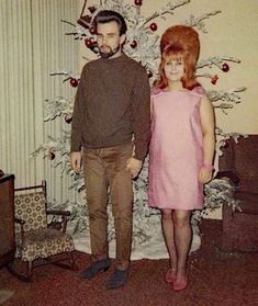 a man and woman standing in front of a christmas tree