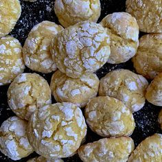 a pile of powdered sugar cookies sitting on top of a black countertop next to each other