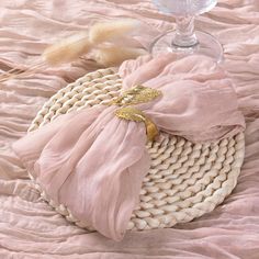 a pink purse sitting on top of a bed next to a wine glass and feather