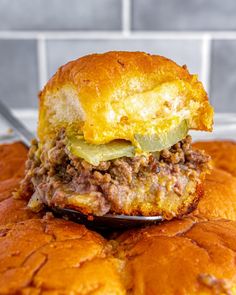 a close up of a sandwich on a spoon with meat and cheese in the middle