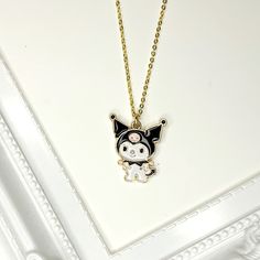 a necklace with a black and white cat hanging from it's side on a gold chain