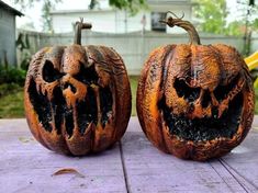 two carved pumpkins sitting on top of a wooden table