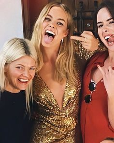 three women are posing for the camera with their mouths open and one is pointing to her right