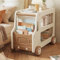 a toy bus with books and magazines in it on the floor next to a bed