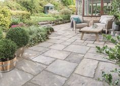 a patio with chairs, tables and potted plants