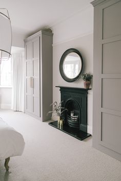 a living room with a fireplace, mirror and white carpeted floor in front of it