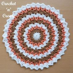 a crochet doily with an orange and white center on a wooden surface