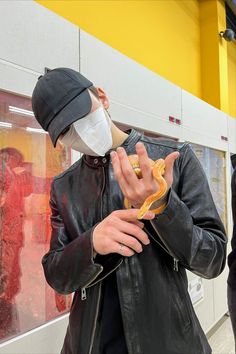 a man wearing a face mask eating a hot dog