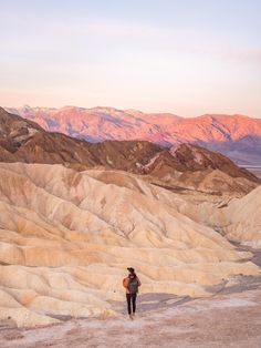 a person standing in the middle of a desert with mountains in the backgroud