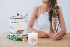 a woman sitting at a table with a cake and glass of wine